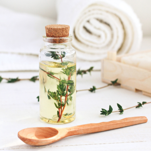 Fresh Tyme oil in a small bottle with wooden spoon and towel